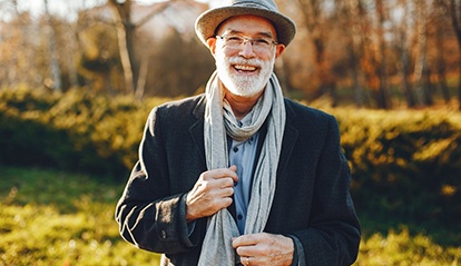 Bearded man with hat and scarf smiling outside