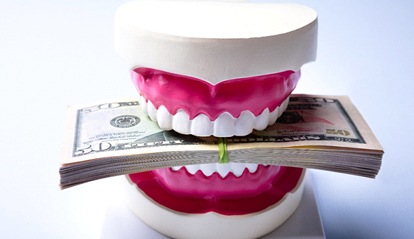 A mouth mold holding a stack of money between the teeth