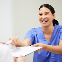 Dental assistant smiling while handing patient form