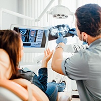A woman looking at a dental X-ray with her dentist