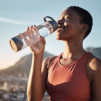 Woman smiling while drinking water on hike