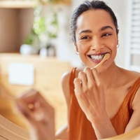 Woman smiling while brushing her teeth