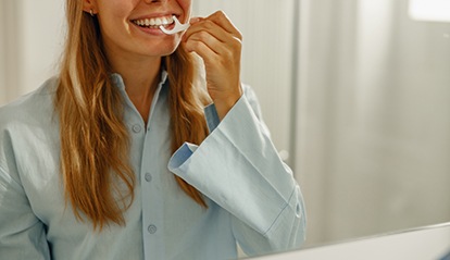 Woman smiling while flossing teeth